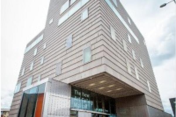 Exterior of the New Art Gallery Walsall, clad in pale terracotta tile with a steel and glass entrance