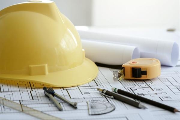 A yellow hard hat and some plans 