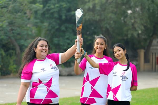 3 women holding up the baton for commonwealth games 