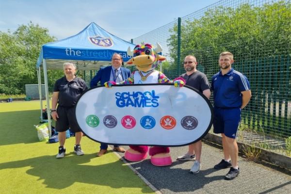 Image shows a group of people with the Birmingham 2022 mascot promoting the School Games