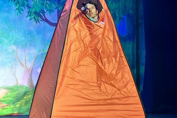 Image depicts an actor on stage in an orange tent performing at Sleeping Beauty panto at Walsall Arena.