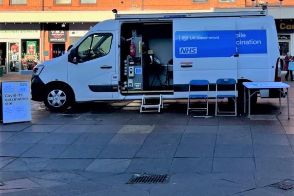 Image shows a mobile vaccination bus in a town centre.