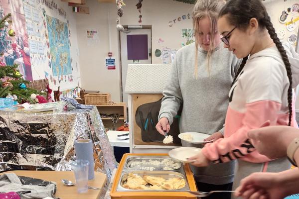 Image shows a young person being served food at the holiday activity food programme.