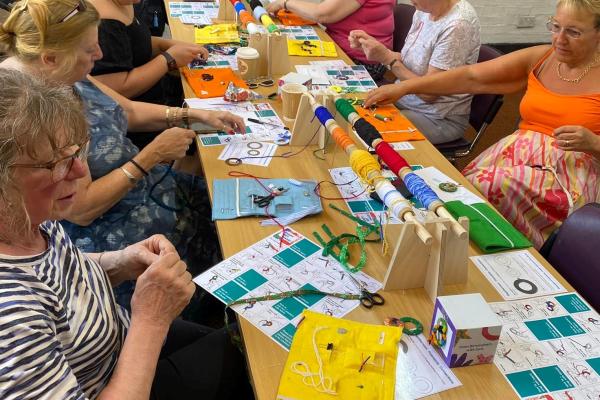 Adults taking part in a craft session around a table