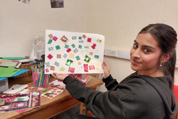 Image shows a girl displaying her artwork.