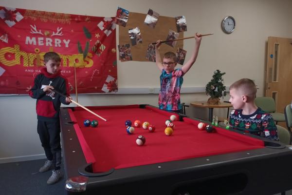 Image shows three boys playing pool at a holiday activity food programme.