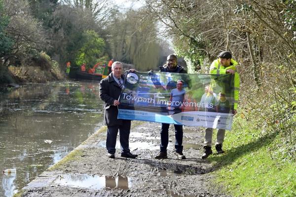 Councillor Andrew with members from Canal and River Trust on a canal towpath holding a banner