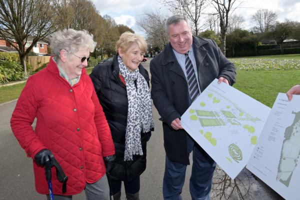 Councillor Andrew showing park improvement plans to two residents walking in the park