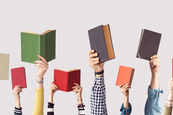 8 books being held up by people's hands