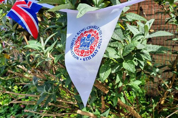 red white and blue coronation bunting against a leafy background