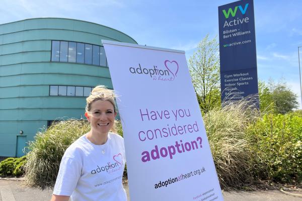 Image of lady holding adoption at heart banner outside Bert Williams Leisure centre