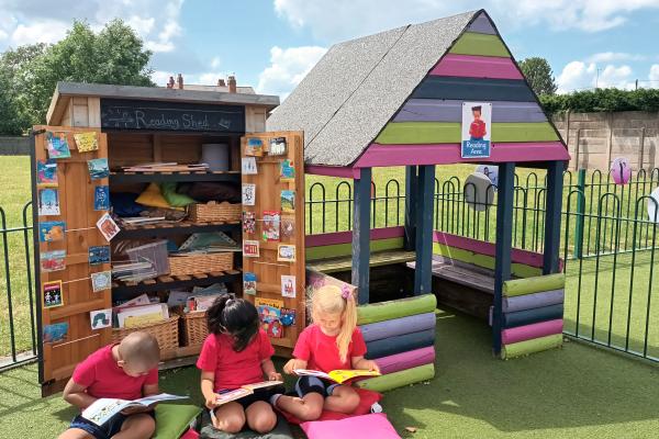 Children reading in Reception classroom outdoor area