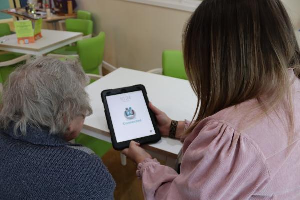 Member of staff showing a resident an ipad