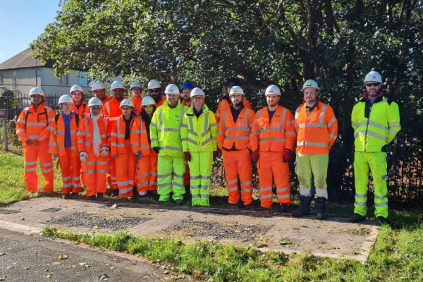 A group of contractors in high-visibility clothing stand together on a path in Willenhall