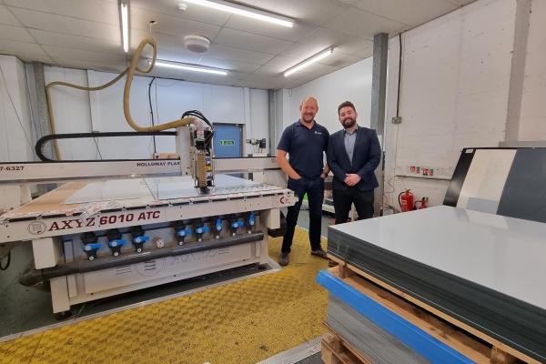 Two men standing next to a large CNC Router within a factory