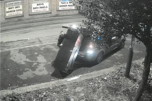 A still frame of CCTV footage where a man is fly-tipping a fridge at the side of a road.