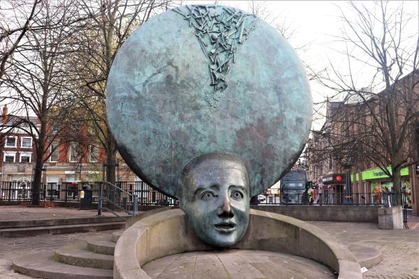 Large sculpture of a head with thoughts and ideas pouring in, set in a town centre square