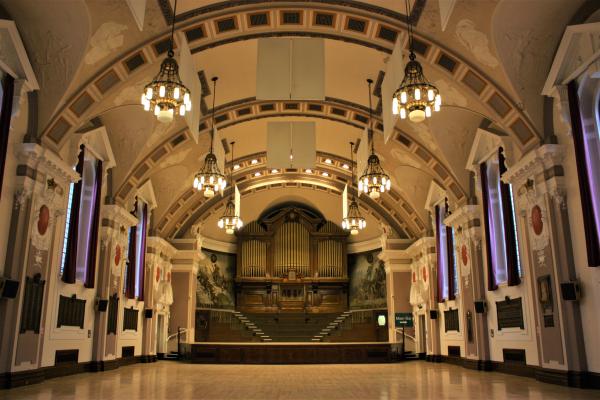 A view of the main stage area in Walsall's Town Hall. Ornate light fittings hang from the decorative ceiling.