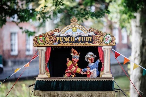 A stage with Punch and Judy puppets waving.