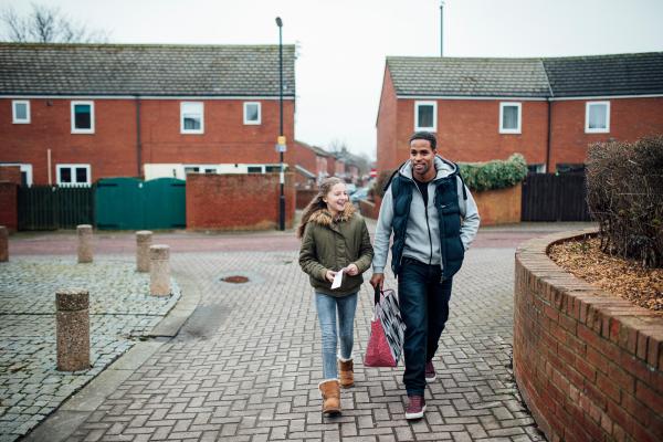 A man and young girl walking through a housing estate