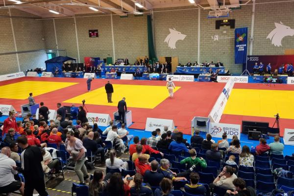 A high angle view of a Judo cup event, the floor is marked out with three large yellow squares 