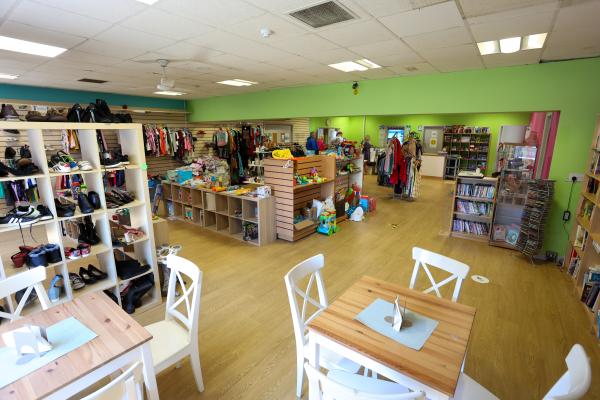 Inside a charity shop with green walls and rails of clothing