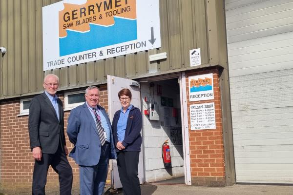 Three people outside the Gerrymet Ltd factory smile at the camera