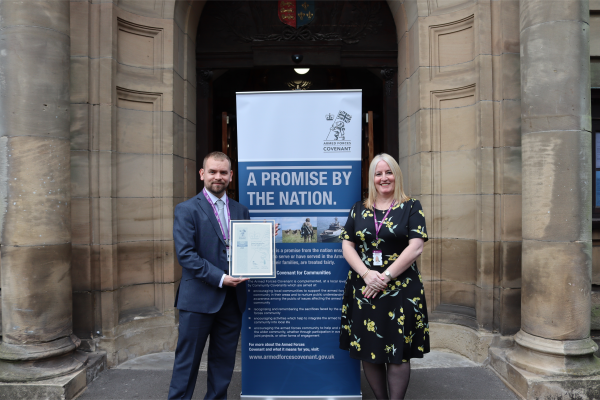 Councillor Adam Hicken and Irene Ramdehal holding silver award outside Walsall Council House