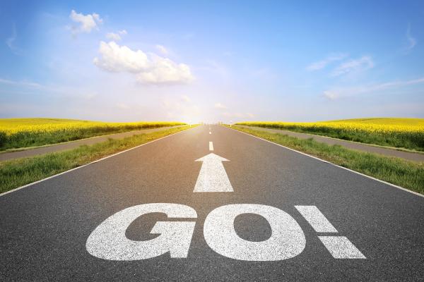 A tarmac road with GO and an arrow pointing ahead in white on the open road