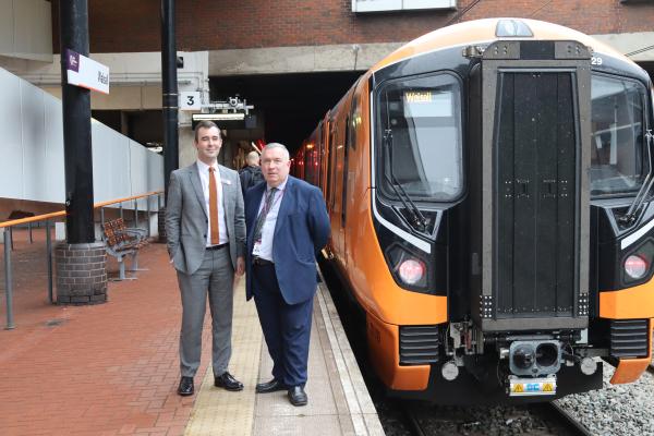 Two men in suits stand beside a train