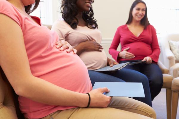 Image depicts a group of three pregnant women at an antenatal clinic.