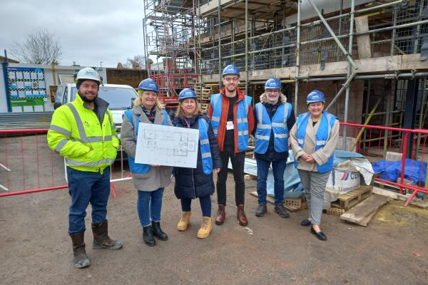 A group of people on a building site wearing high-vis jackets and hard hats