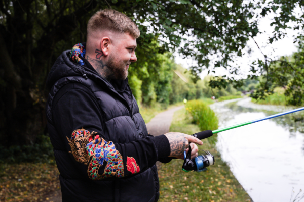 Image depicts a man fishing by the canal.