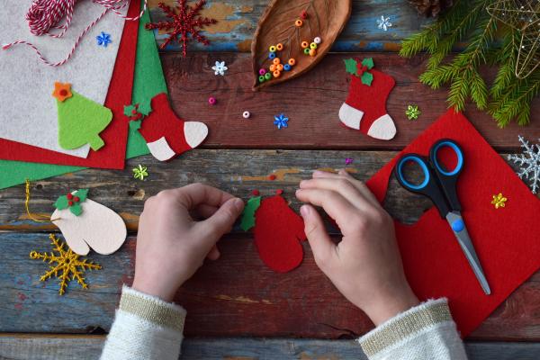 Christmas themed crafting materials and a child's hands making decorations