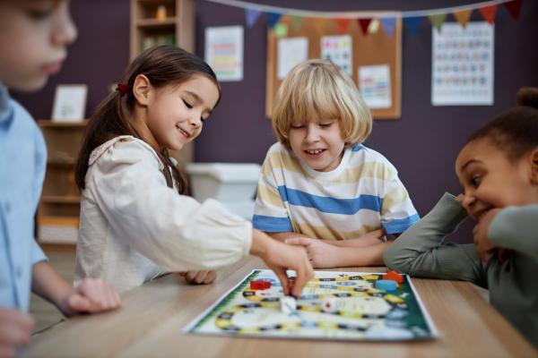 A group of four smiling children playing a board game on a table