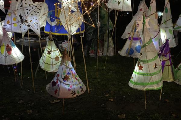 Image depicts decorated lanterns in various shapes and sizes lit up in the dark.