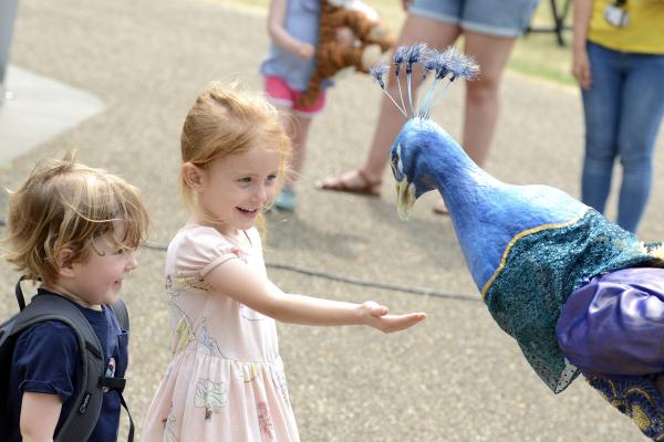 Children smiling at a peacock puppet