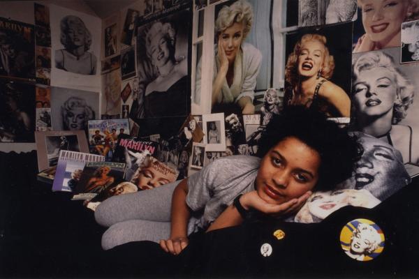 A girl lying on a bed surrounded by Marilyn Monroe memorabilia