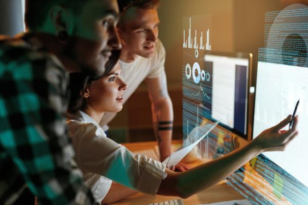 Three software developers looking at a computer monitor.