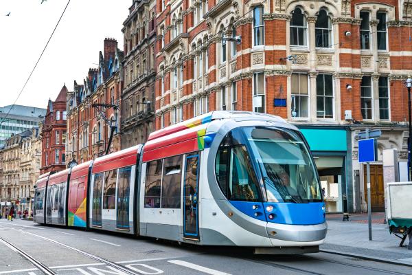 A tram is in a busy street in Birmingham city centre.