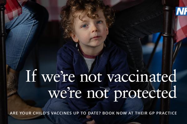 Image depicts a boy under a table. Text: if we're not vaccinated we're not protected.