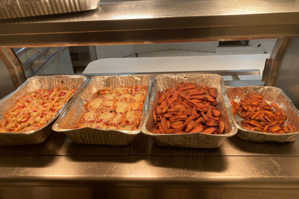 Image depicts cooked food in metal trays on a servery.