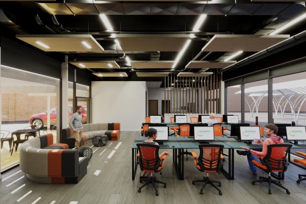 A bright modern office space with orange and grey seating and a bank of computers