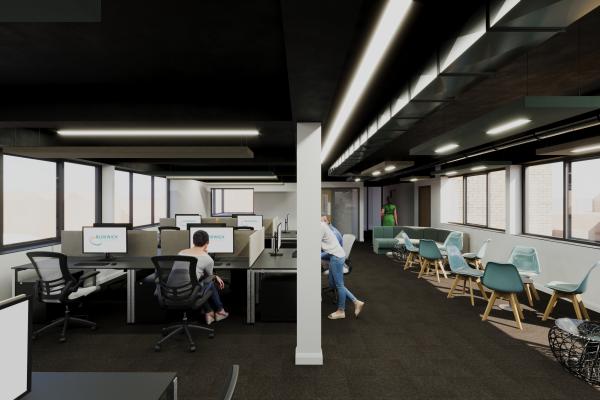 A bright modern office space with teal and grey seating and a bank of computers