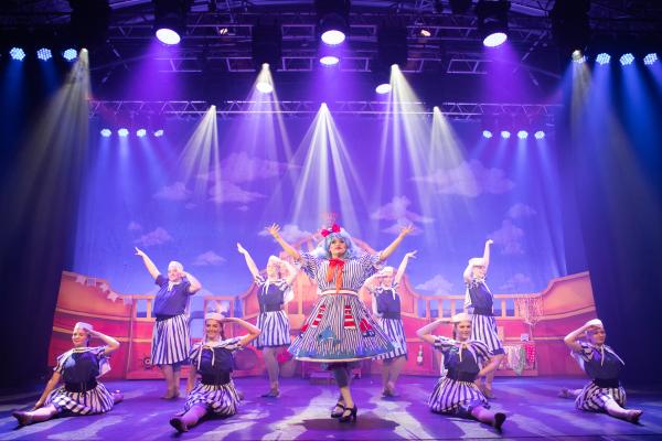 Pantomime performers posing on a well lit stage