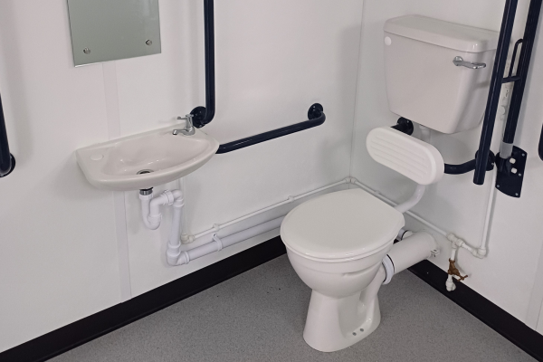 A new toilet and sink in a unit with grey floor and white walls