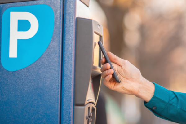 Image depicts someone paying for parking through contactless on their mobile phone.