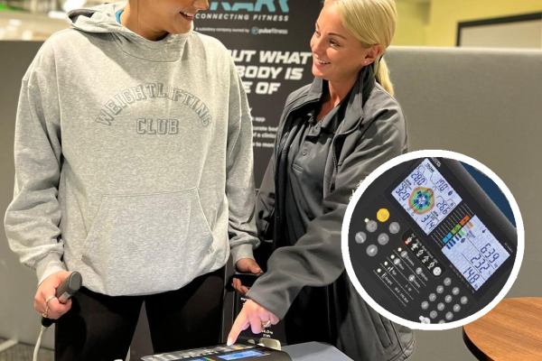 Female instructor standing with a female customer showing how to use a set of scales indoor in leisure centre reception