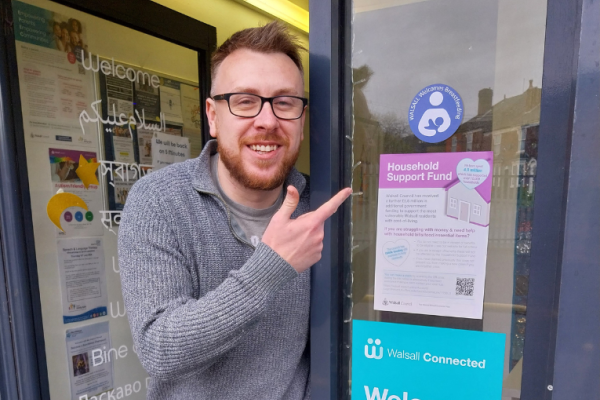 Image depicts Nike from MindKind Projects pointing towards the Walsall Welcomes Breastfeeding sticker.