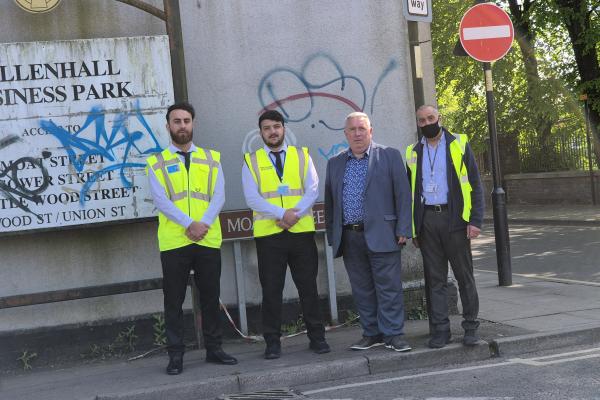 a group of four men standing beside a derelict factory